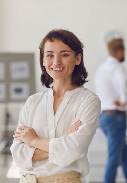Portrait of happy successful woman in her workplace. Confident female company employee or department manager in office. Business lady in formal wear with arms folded looking at camera and smiling